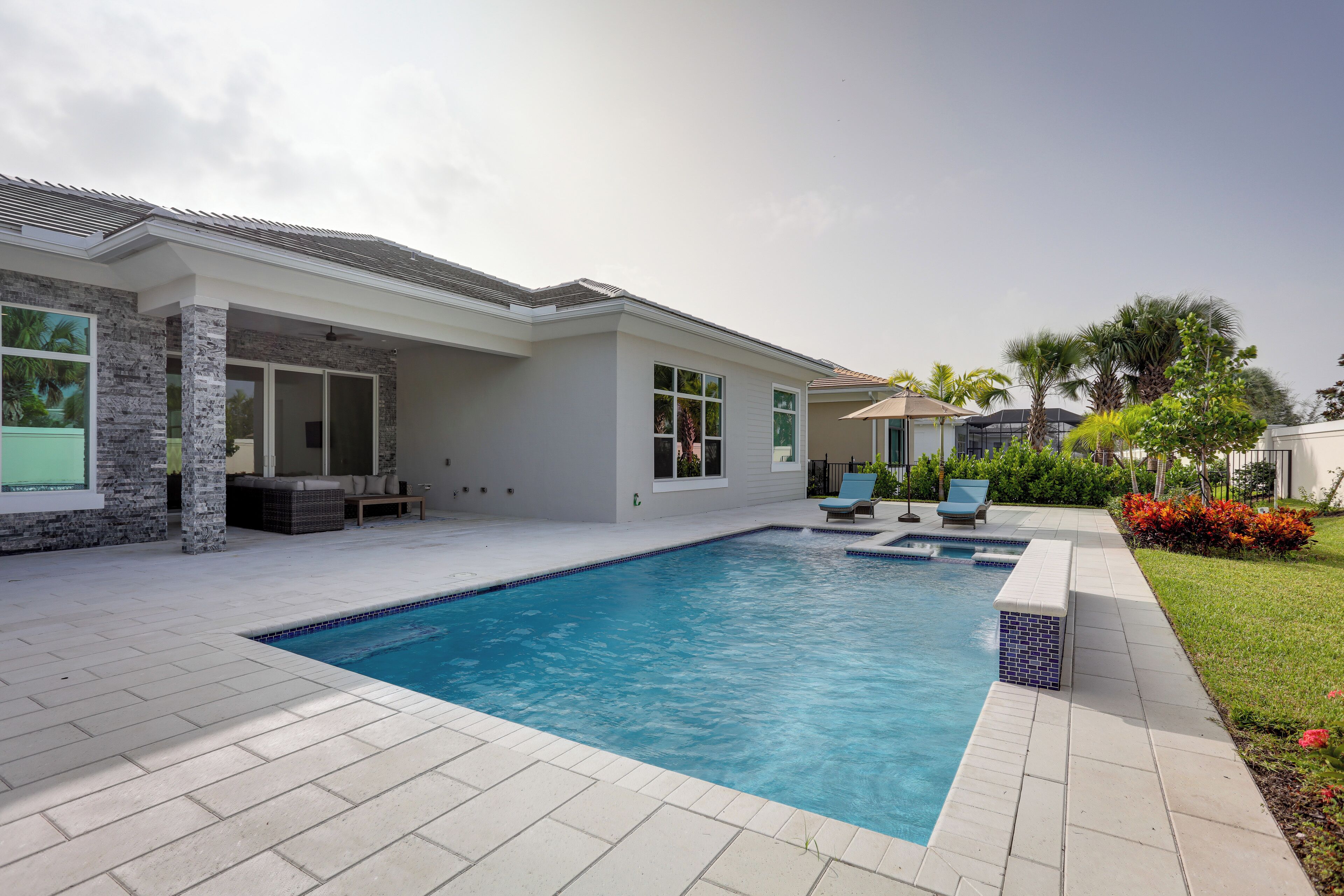 A modern house with a swimming pool, outdoor seating, and a well-maintained garden.