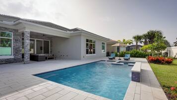 A modern house with a swimming pool, outdoor seating, and a well-maintained garden.
