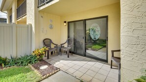 A patio area with a sliding glass door, outdoor chairs, and a small garden with plants. - Daytona Beach Shores Condo Rental: Walk to Beach! (Daytona Beach)