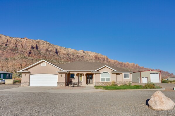 A single-story house with a garage, a front porch, and a driveway. - Moab Home w/ Pool - 14 Mi to Arches National Park! (Moab)