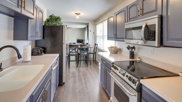 A modern kitchen with grey cabinets, a stainless steel microwave, a black stove, and a sink. - Lovely South Bend Home ~ 3 Mi to Dtwn & Notre Dame (South Bend)