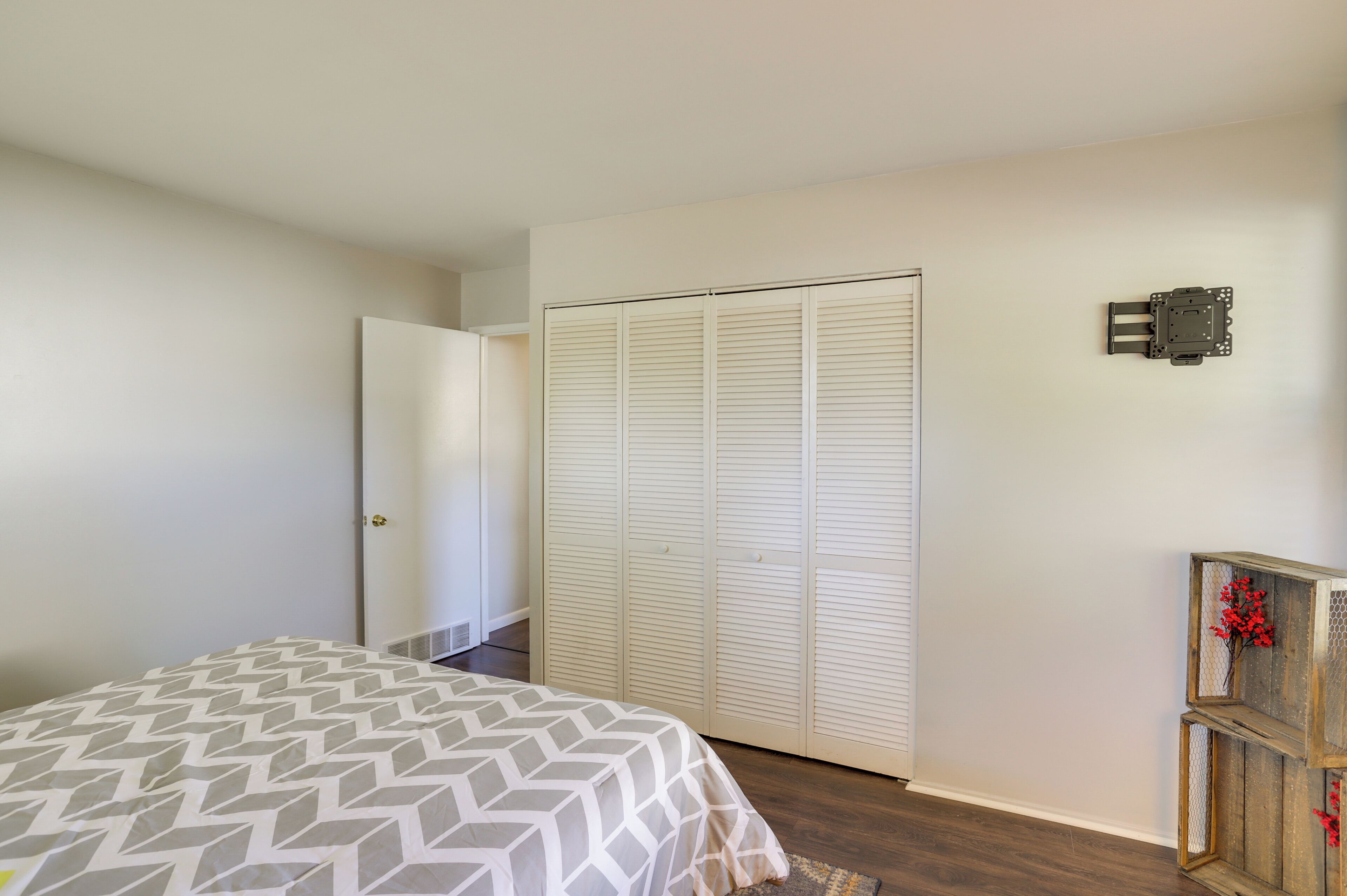 A bedroom with a bed, a closet, and a wall-mounted TV.