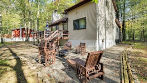 Eine Hütte mit einer Terrasse, Sitzgelegenheiten im Freien und einer Feuerstelle.