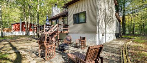 A cabin with a deck, outdoor seating, and a fire pit.