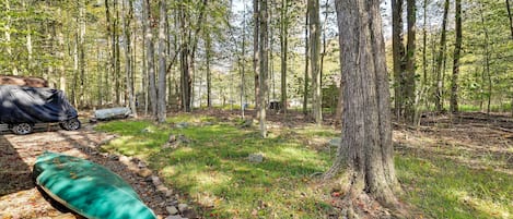 En campingplats med ett tält, ett avskärmat sittområde och en naturskön skogsmiljö.