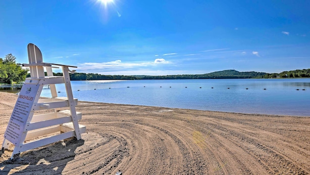 Ein Strand mit einem Holzschild und blauem Himmel.