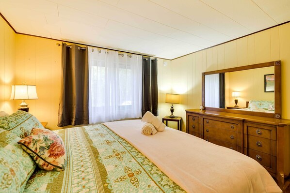A hotel room with a bed, a dresser, a mirror, and two lamps.
