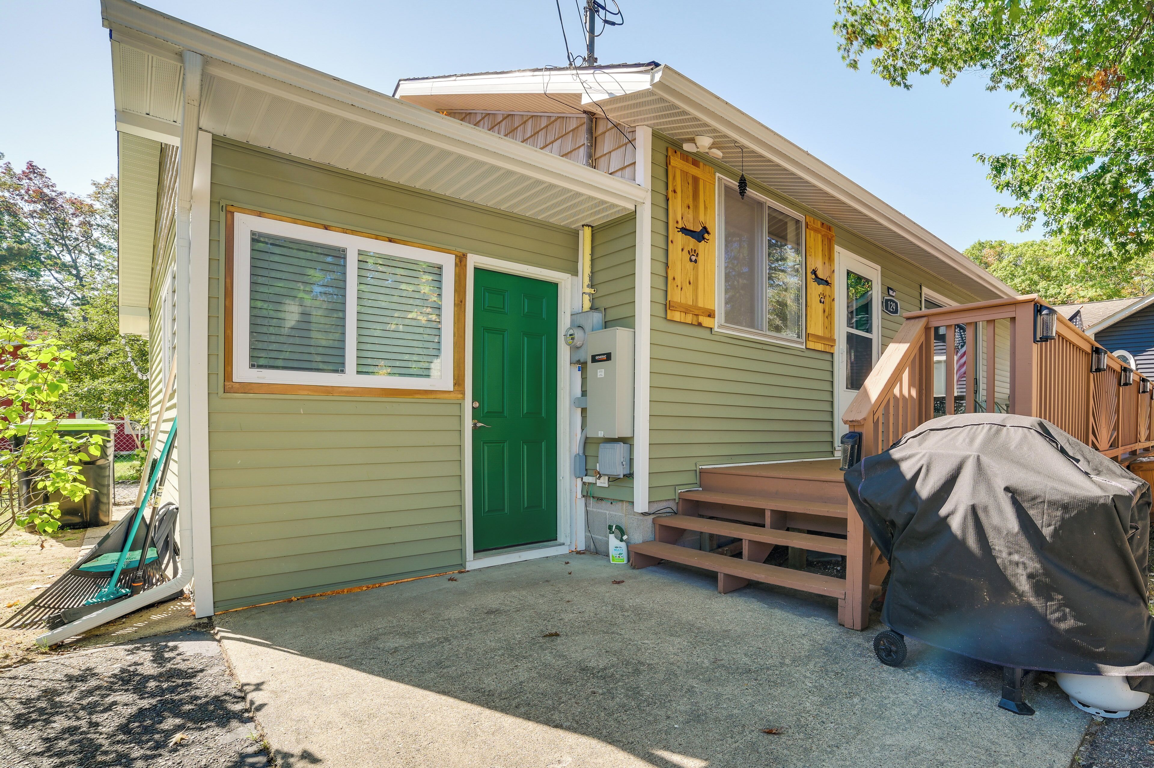 A two-story house with a green door, a covered grill, and a wooden deck.