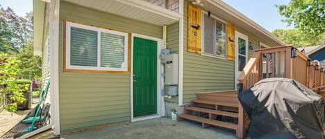 A two-story house with a green door, a covered grill, and a wooden deck.