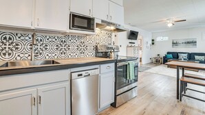 A modern kitchen with white cabinets, a stainless steel dishwasher, a built-in oven, and a microwave. - Higgins Lake Cottage w/ Private Fire Pit & Grill! (Roscommon)