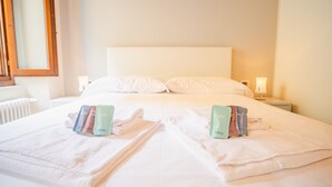 Un lit bien fait, avec deux jeux de serviettes et des produits de toilette de voyage de chaque côté.