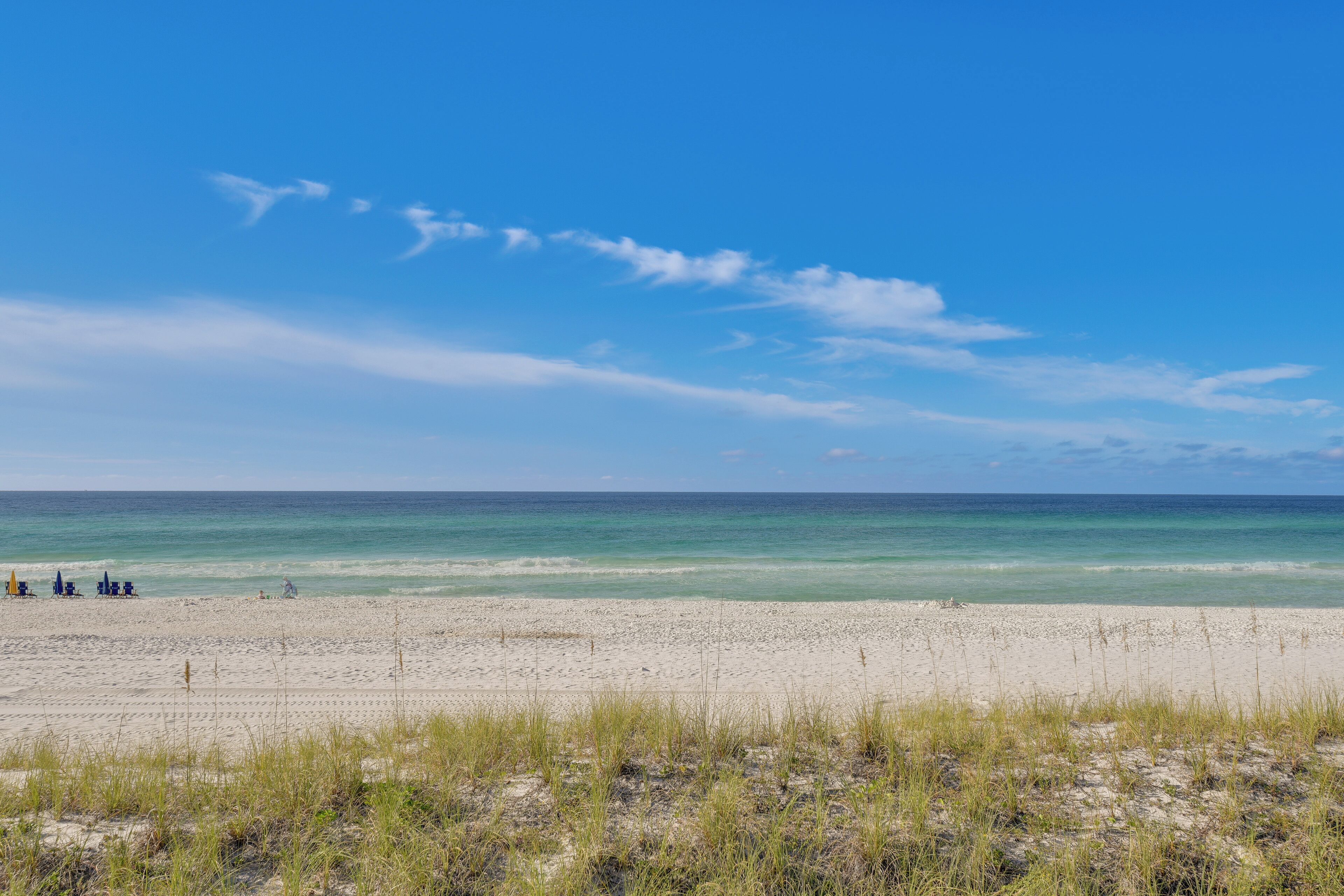 Ein Strand mit blauem Himmel und ruhigem Wasser.