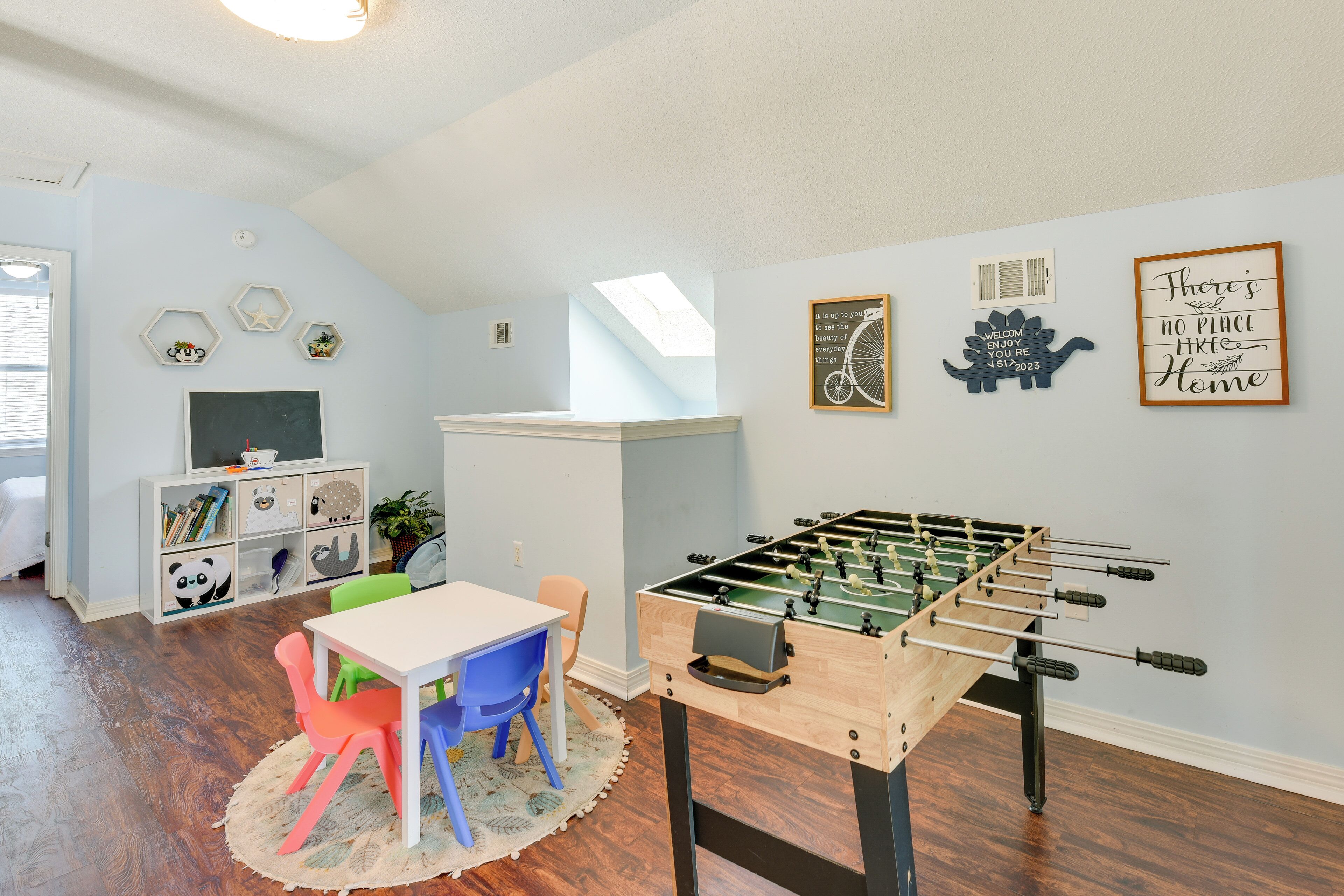 A cozy room with a foosball table, a desk with chairs, and a bookshelf.