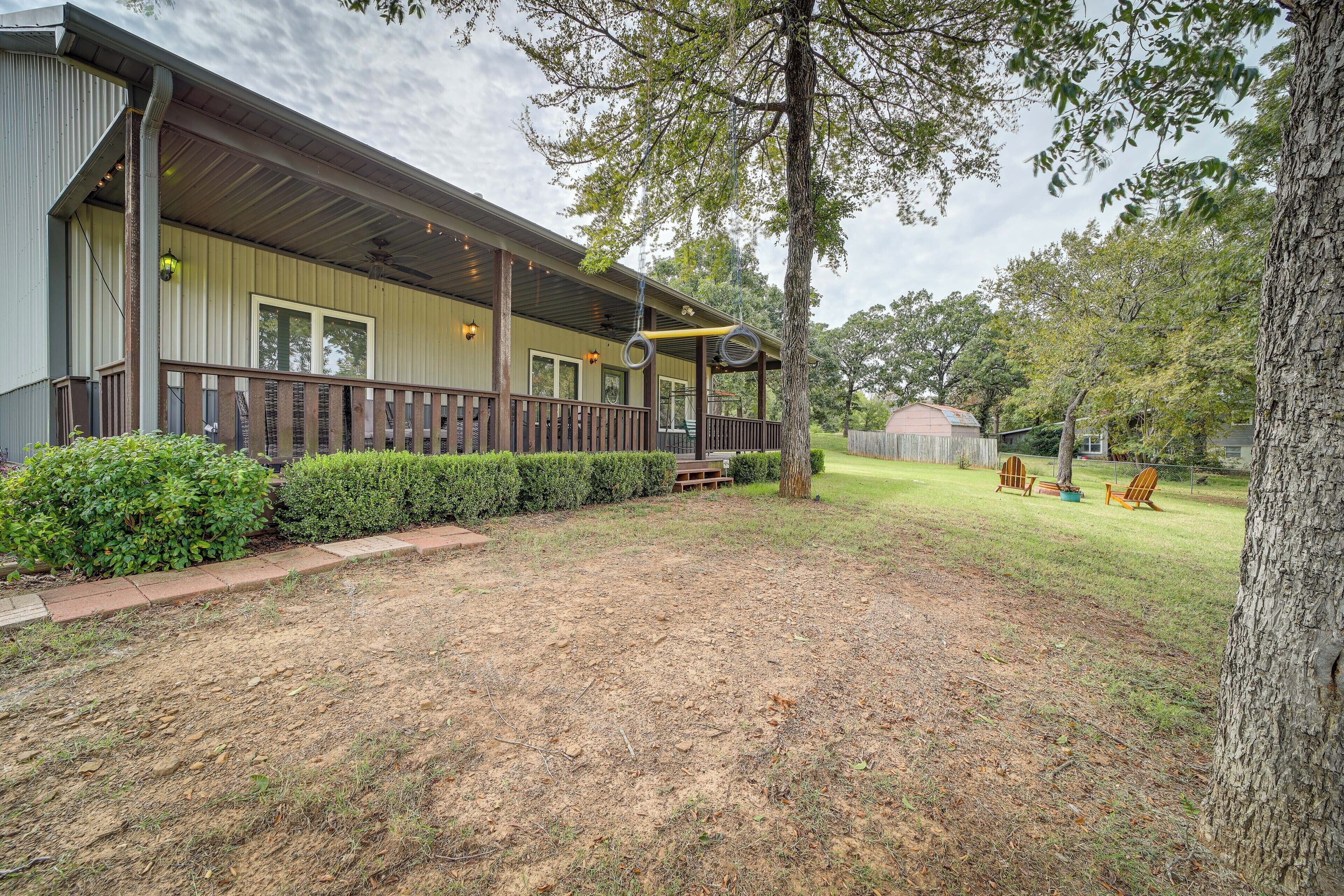 A house with a covered porch, a fenced yard, and a tree.