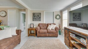 A living room with a brown leather sofa, a wooden coffee table, and a TV stand with shelves. - Oklahoma Home Near Lake w/ Patio, Grill & Chiminea (Fort Cobb)