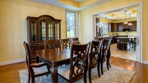 A dining room with a wooden table and chairs, a large cabinet, and a patterned rug.