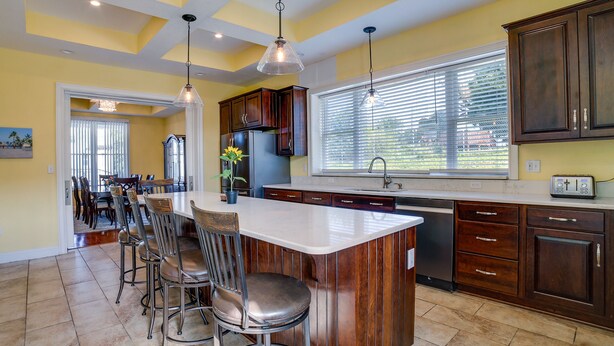 A kitchen with a large island, dark wooden cabinets, and pendant lighting.