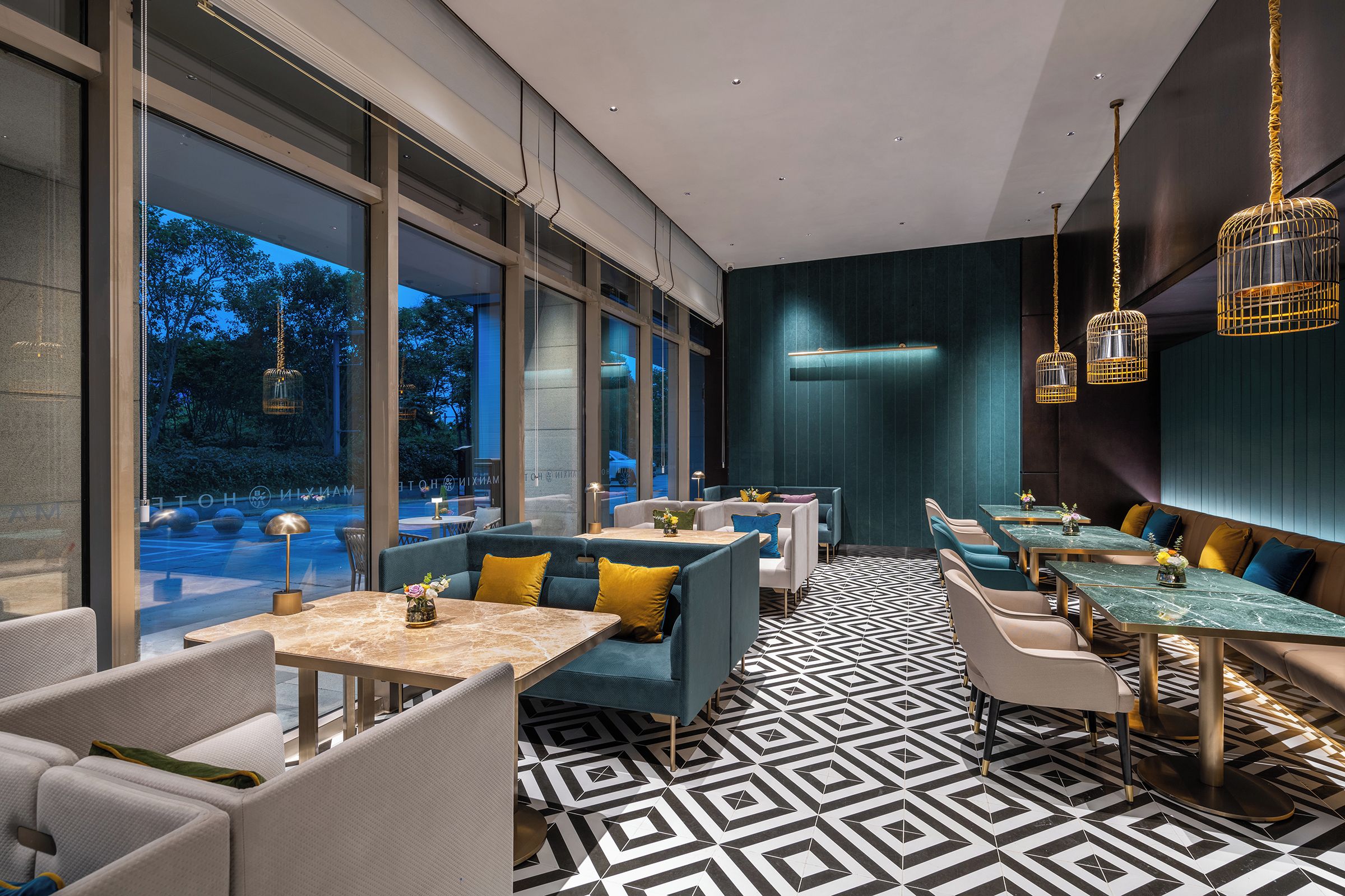 Un restaurante moderno con ventanas amplias, suelo de estampado geométrico y mobiliario contemporáneo.