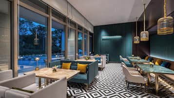 Un restaurante moderno con ventanas amplias, suelo de estampado geométrico y mobiliario contemporáneo.