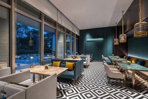 Un restaurante moderno con ventanas amplias, suelo de estampado geométrico y mobiliario contemporáneo.