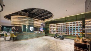 Una moderna zona de recepción con un mostrador curvo, una pared de discos de vinilo y una patineta.