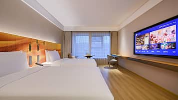 A hotel room with two beds, a desk, a chair, a TV, and a window with curtains.