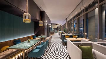 A modern interior with a long dining area, seating, and a patterned floor.