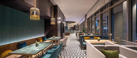 Un interior moderno con una amplia zona de comedor, asientos y un suelo estampado.