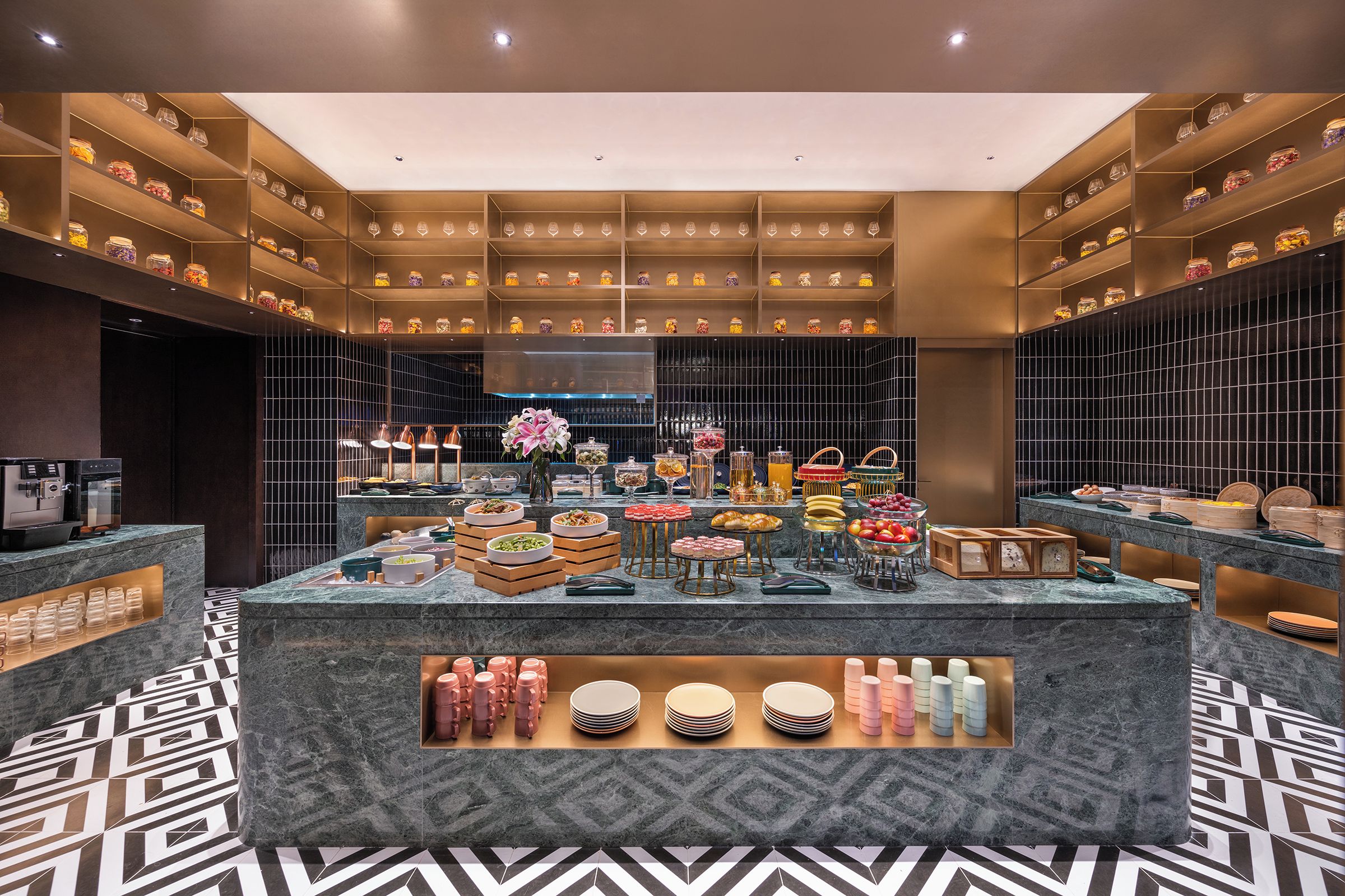 Un área de desayuno moderna y bien iluminada, con una isla central, repisas con frascos y un piso con diseño.