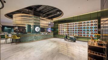A modern reception area with a curved counter, a wall of vinyl records, and a scooter.