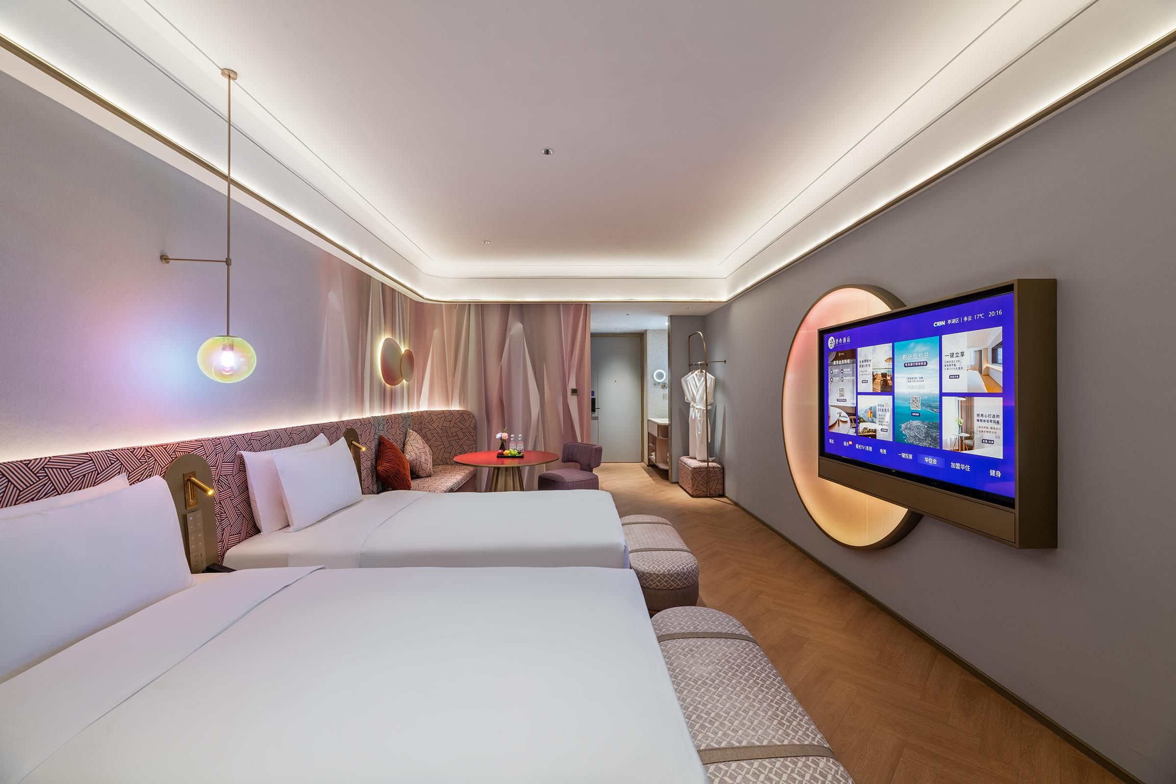 A hotel room with two beds, a TV mounted on the wall, and a small table with a vase of flowers.