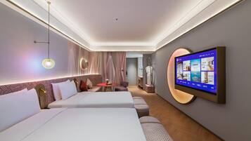 A hotel room with two beds, a TV mounted on the wall, and a small table with a vase of flowers.