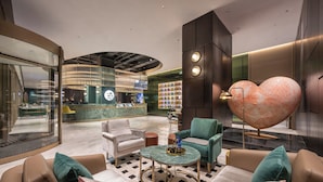 A modern lobby with a curved reception desk, seating area with leather sofas, a marble floor, and a large heart-shaped decorative piece. - Manxin Hotel Yancheng Economic Development Zone (Yancheng)