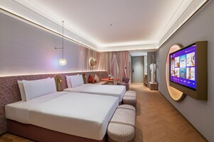 Habitación de hotel con dos camas, un televisor, una mesita y una zona de estar.