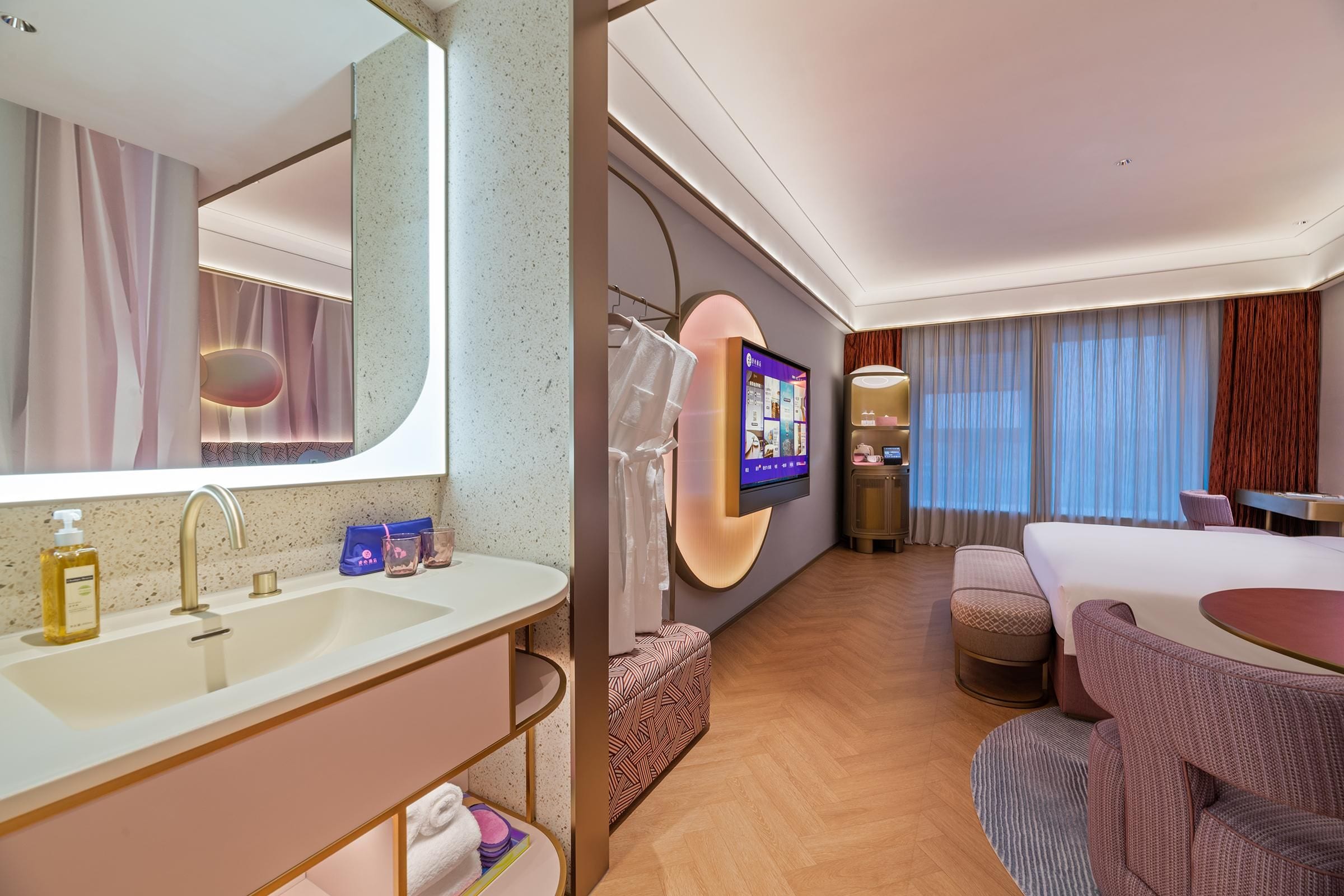 Quarto de hotel com um espelho grande, televisão, cama, sofá e uma mesinha.