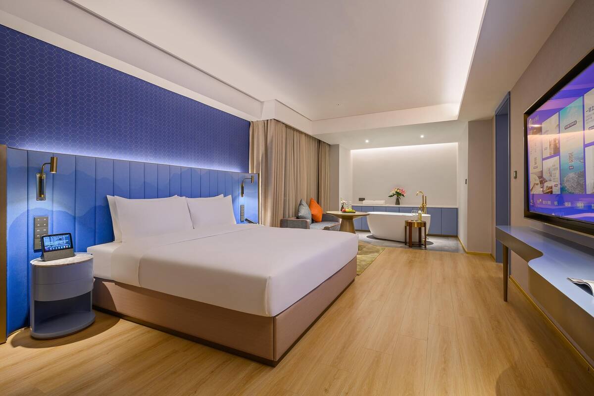 Ein modernes Hotelzimmer mit einem großen Bett, Nachttisch und einem Flachbildfernseher.