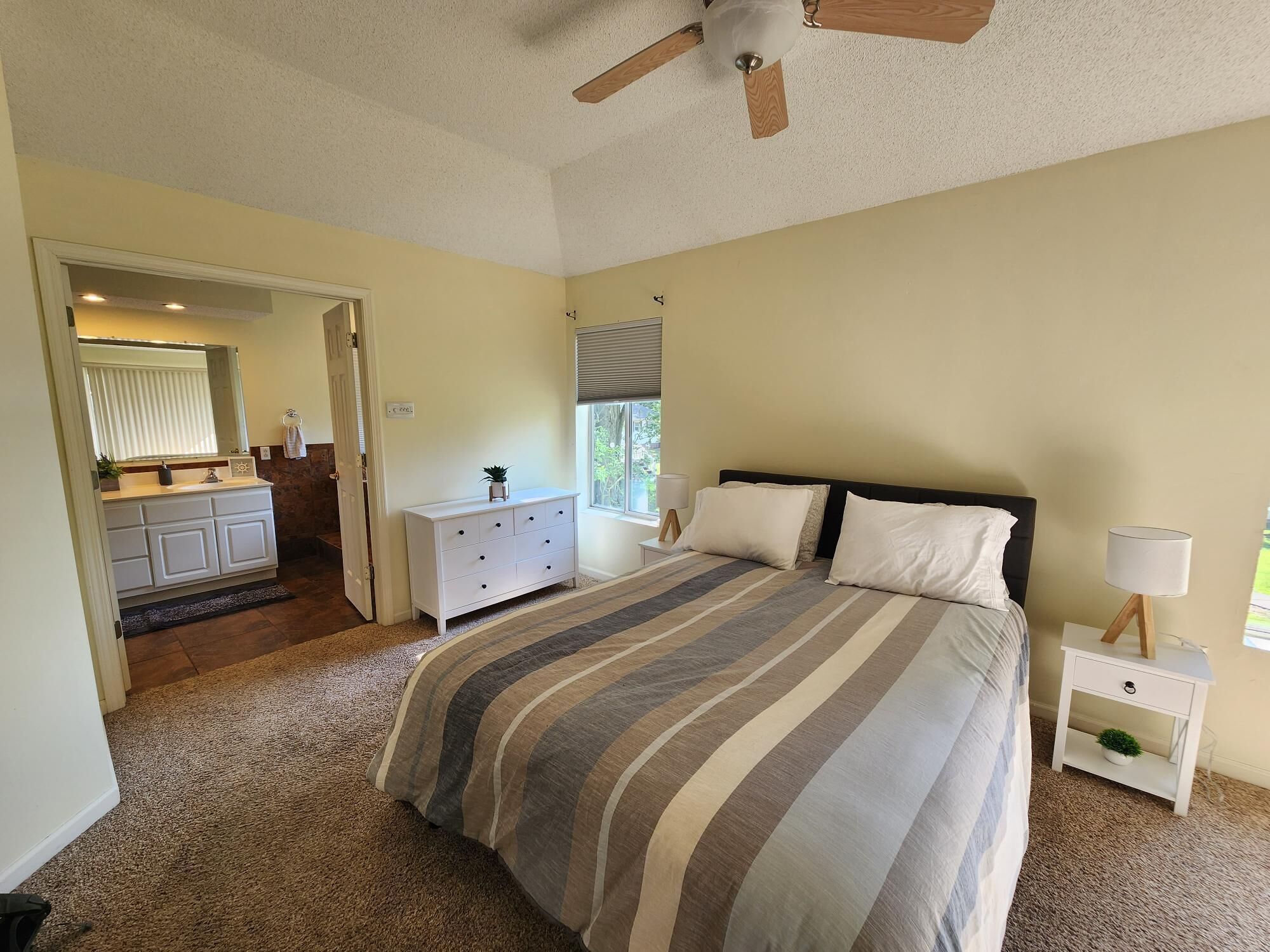 A bedroom with a bed, nightstand, and a ceiling fan.