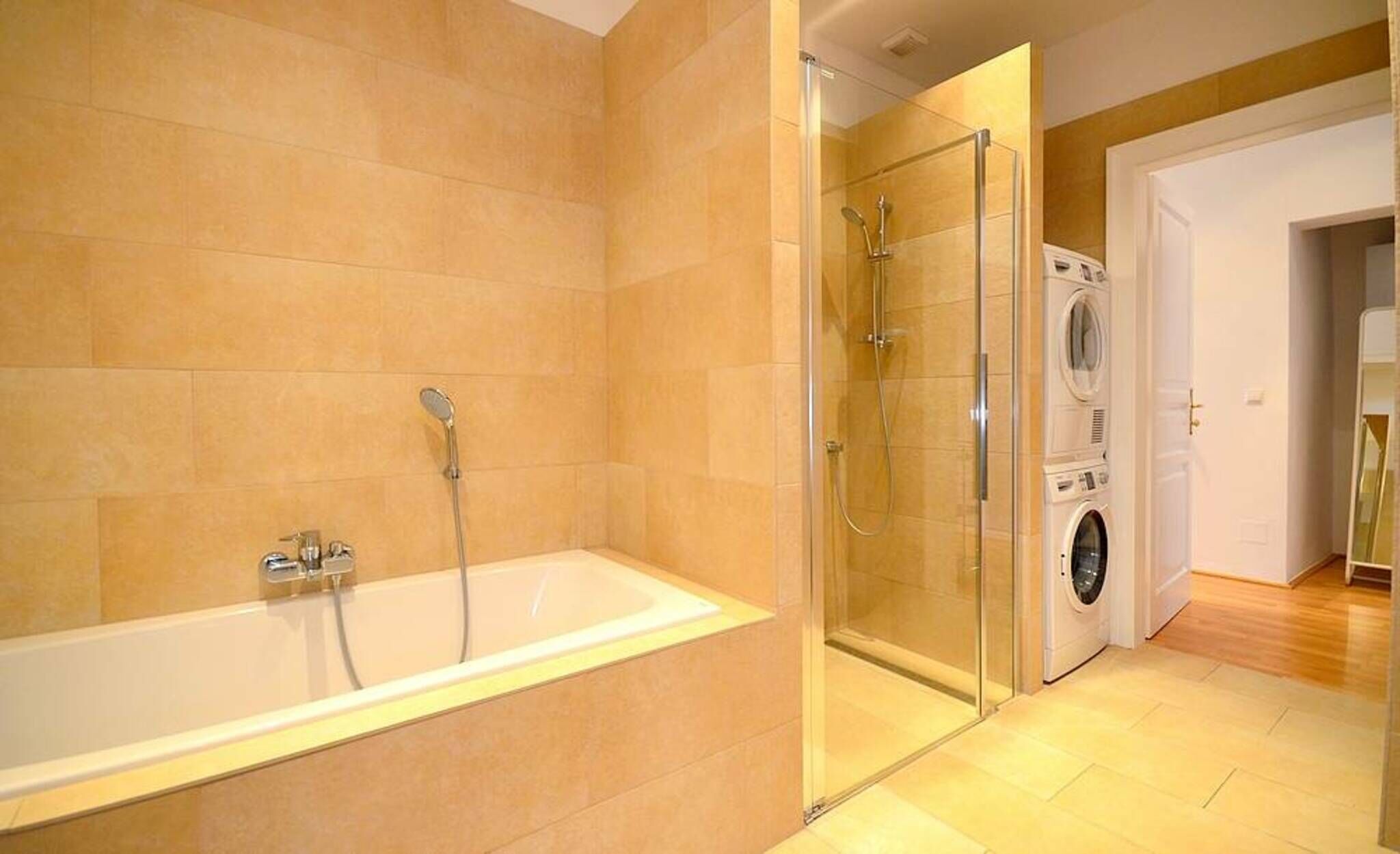 A modern bathroom with a bathtub, shower, and a washing machine.
