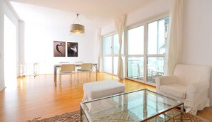 A spacious living room with a glass coffee table, a white sofa, and a dining area with chairs. - Vienna Residence, Brünnlbad - Alsergrund #6270 (Vienna)