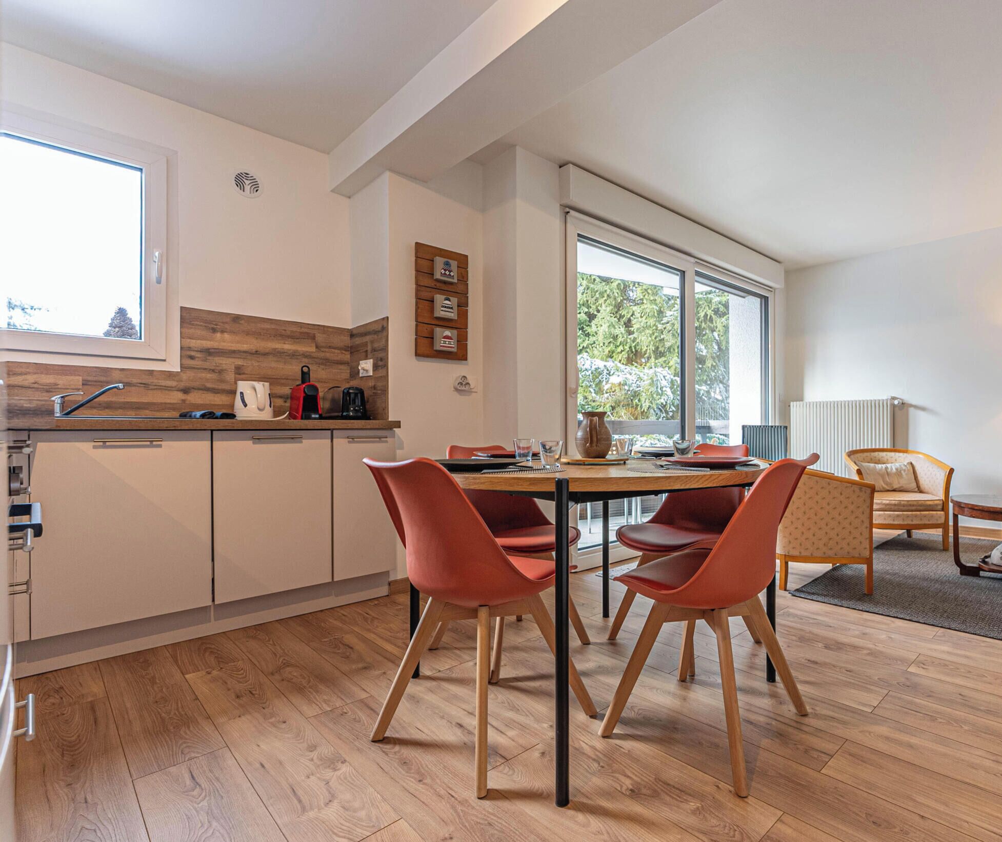 Une cuisine moderne avec un coin repas, un plancher en bois et de grandes fenêtres.