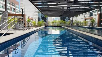Swim laps in a spacious pool surrounded by a glass enclosure offering stunning views of the urban skyline.