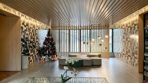 A modern interior with a geometric patterned wall, a Christmas tree, and a seating area with a glass coffee table. - Nun Vila Nova 2503 - Vila Nova Conceição (São Paulo)