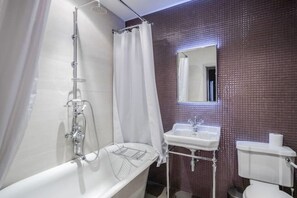 Et badeværelse med badekar, vask og toilet.