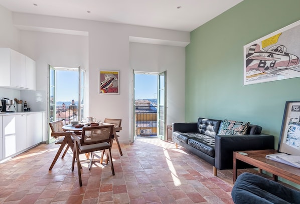 Un salón amplio con una mesa de comedor, un sofá y vistas a través de un ventanal.