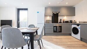 A modern kitchen with grey cabinets, a built-in oven, and a washing machine. - GuestReady - Tranquil Vauxhall Stay (Liverpool)
