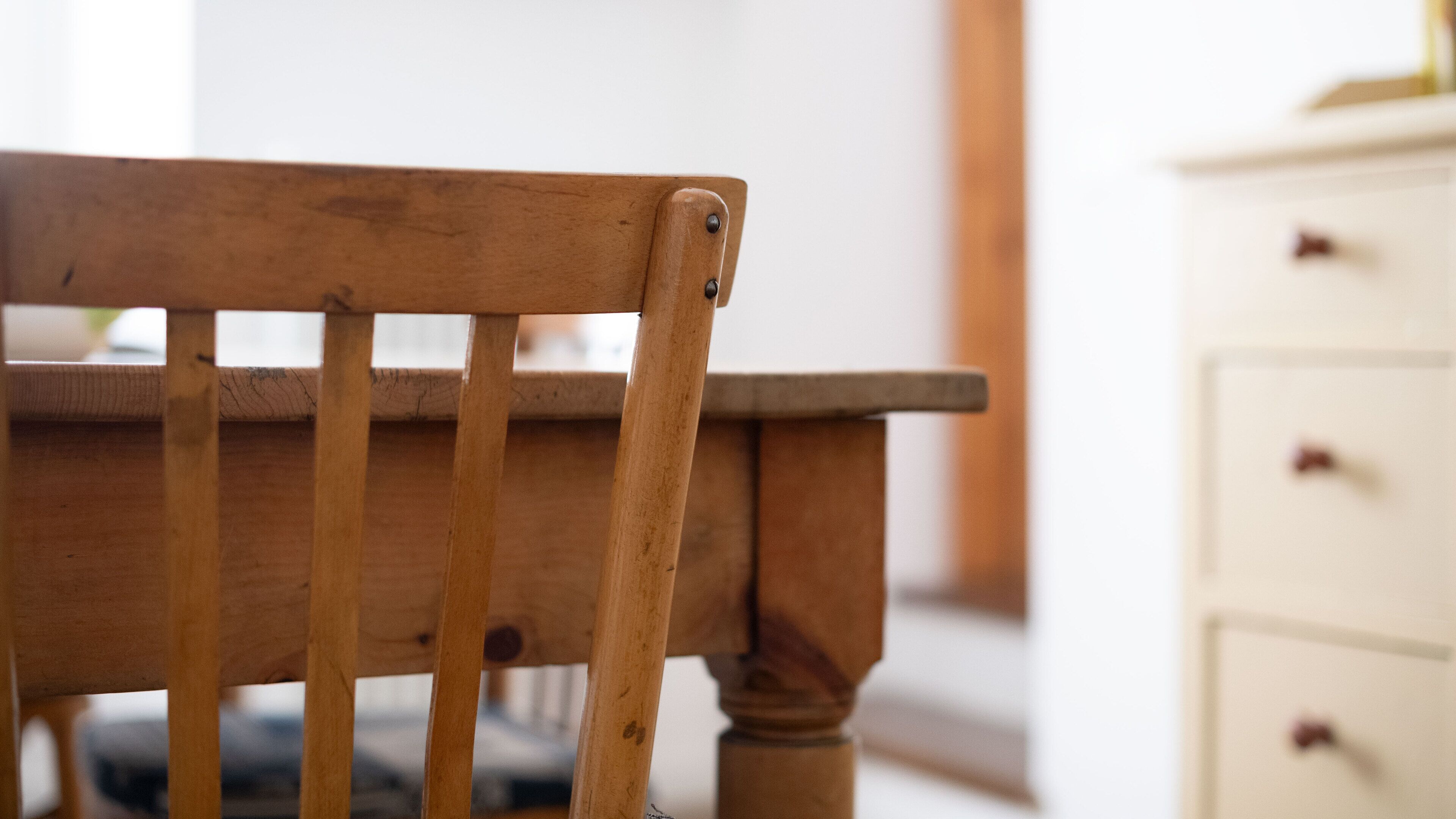 A wooden chair with a slatted backrest and a wooden armrest.