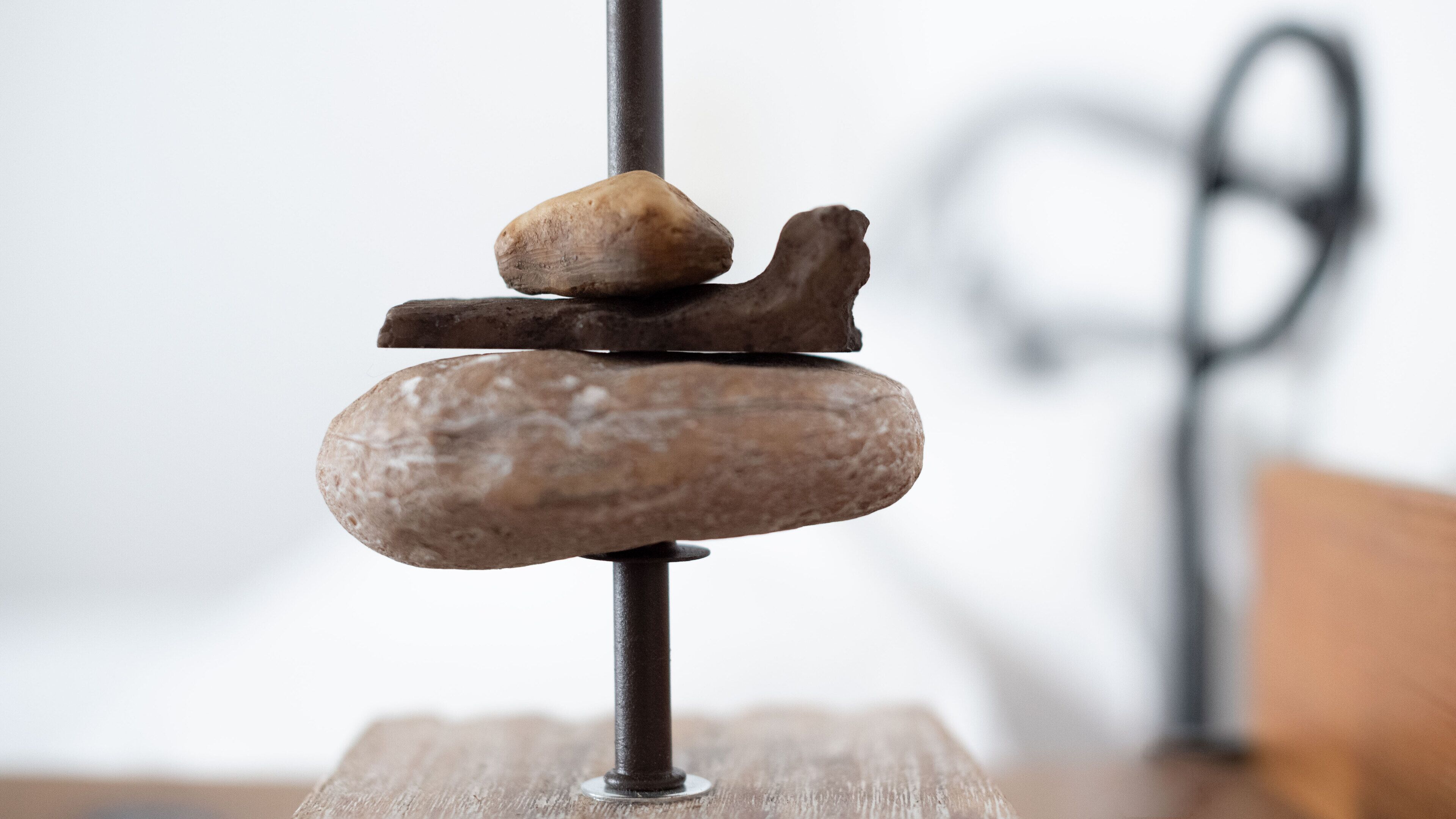 A balance scale with three stones on one side and a pair of scissors on the other.