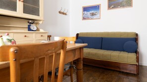 Una habitación acogedora con una mesa de comedor de madera, un sofá azul y un armario de madera con una balanza.