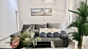 Una sala de estar moderna con un sofá gris, una mesa de comedor y una planta en maceta.