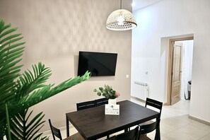 A dining area with a table, chairs, a TV mounted on the wall, and a potted plant. - Central apartment on Calle Infantas (Madrid)